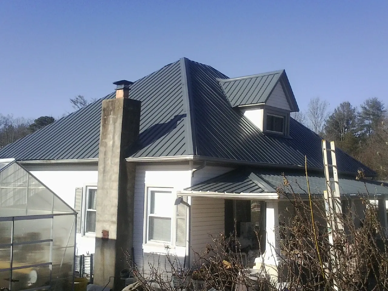 Dark blue standing seam metal roof on a white farmhouse with dormer — Slate & Tile Roof Repair by Roofing Brothers in Pauline