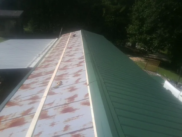 Old rusted panels beside newly installed green metal roofing — Wind Damage Roof Repair by Roofing Brothers in Pauline