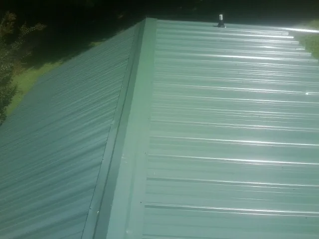 New green metal panels meeting at the ridge of a roof — Flat Roof Repair work by our crew in Pauline