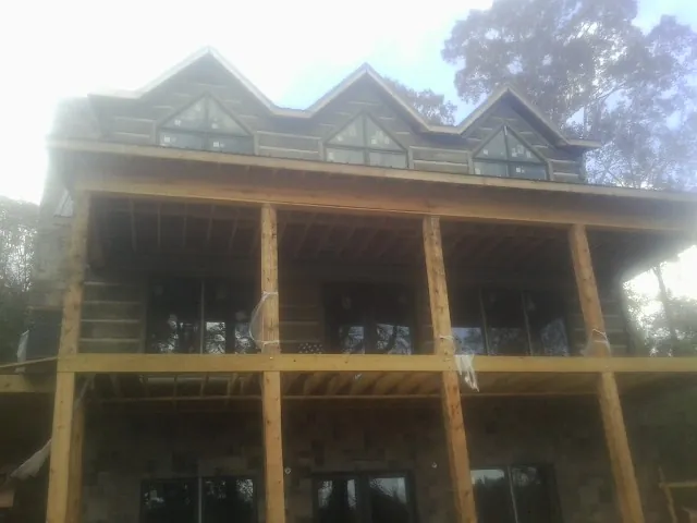 Dormers and porch framing on a large log home under construction — Roof Coating work by our crew in Pauline