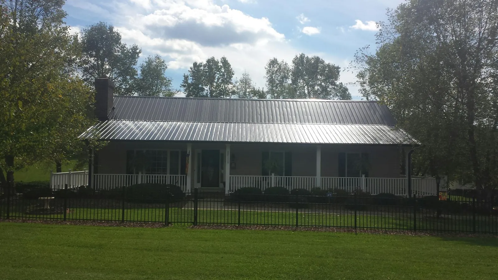Gray metal roof on a brick ranch with a full width front porch — Gutter Guard Installation work by our crew in Pauline
