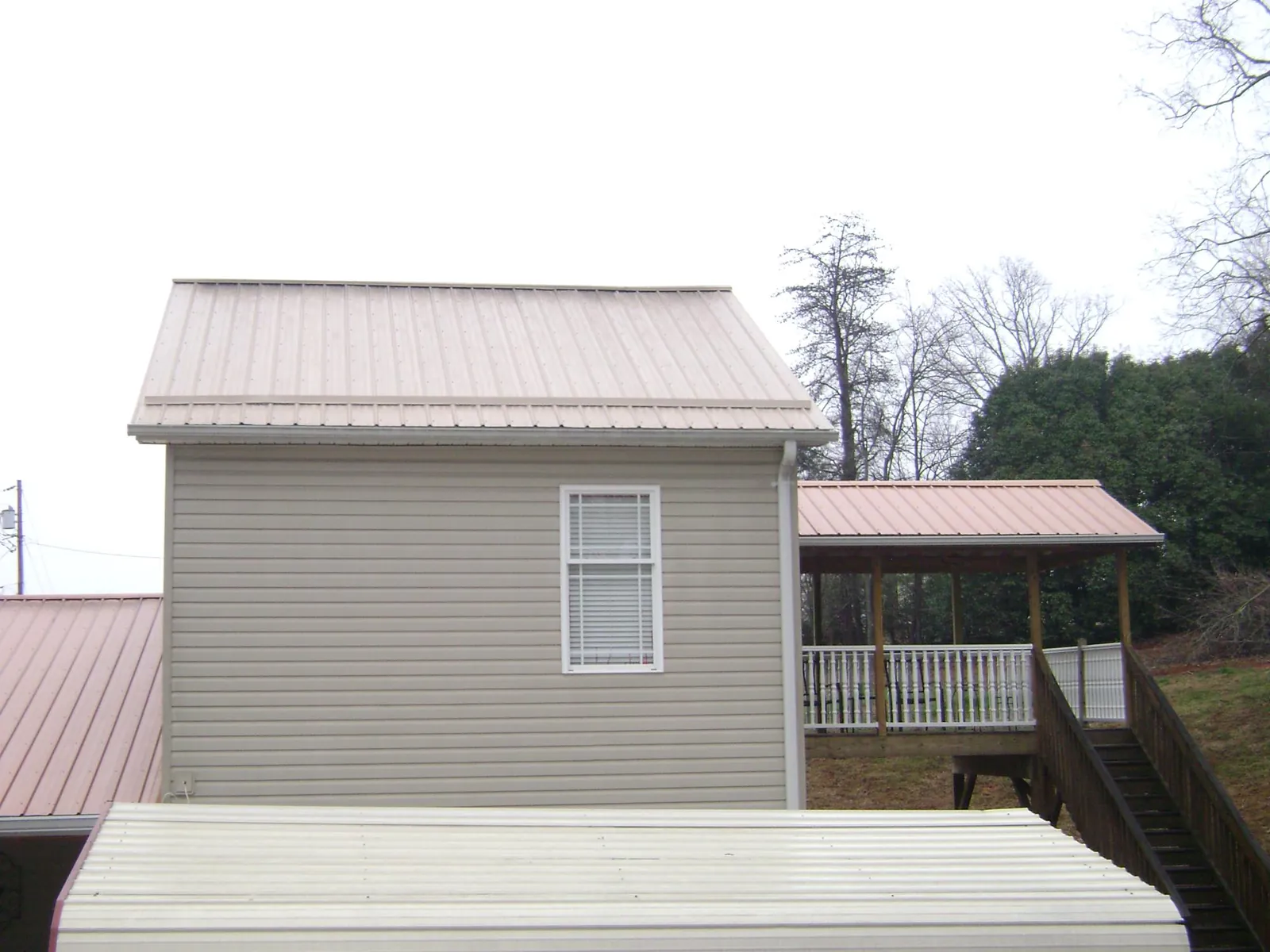 Tan metal roofs on a two story addition and attached porch, from a Roof Replacement job in Pauline